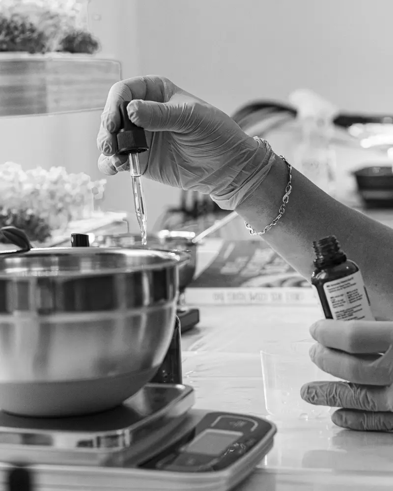 Mains gantées préparant un produit, en noir et blanc