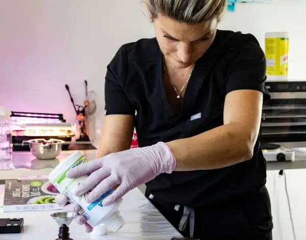 Stéphanie prépare un flacon au comptoir de son salon, vue en plongée